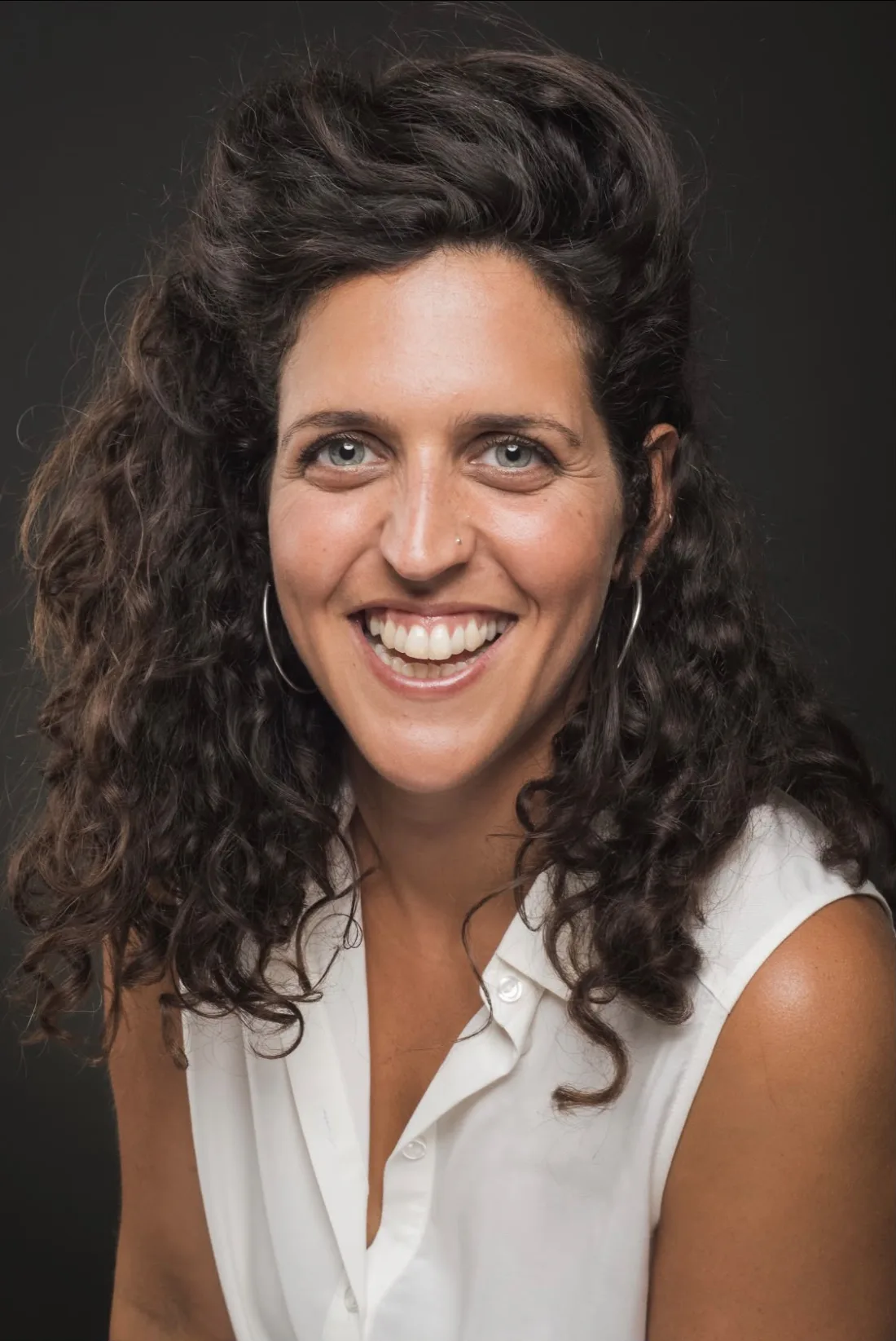 עופרי פוקס צוחקת, בחולצה לבנה על רקע כהה